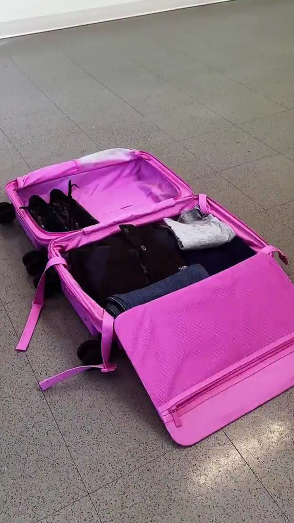 overhead flat lay of an open front-pocket carry-on showing camera gear, lenses, and a laptop sleeve