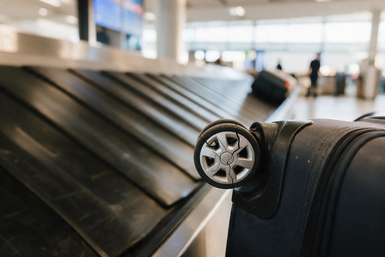 cracked suitcase wheel next to airport carousel